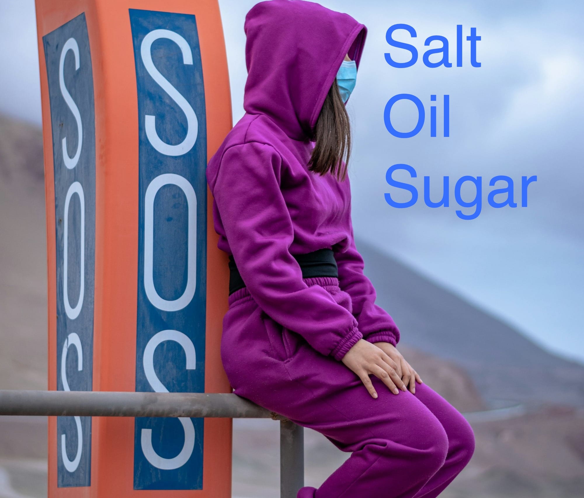 woman in purple hoodie and purple scarf standing on brown wooden fence during daytime