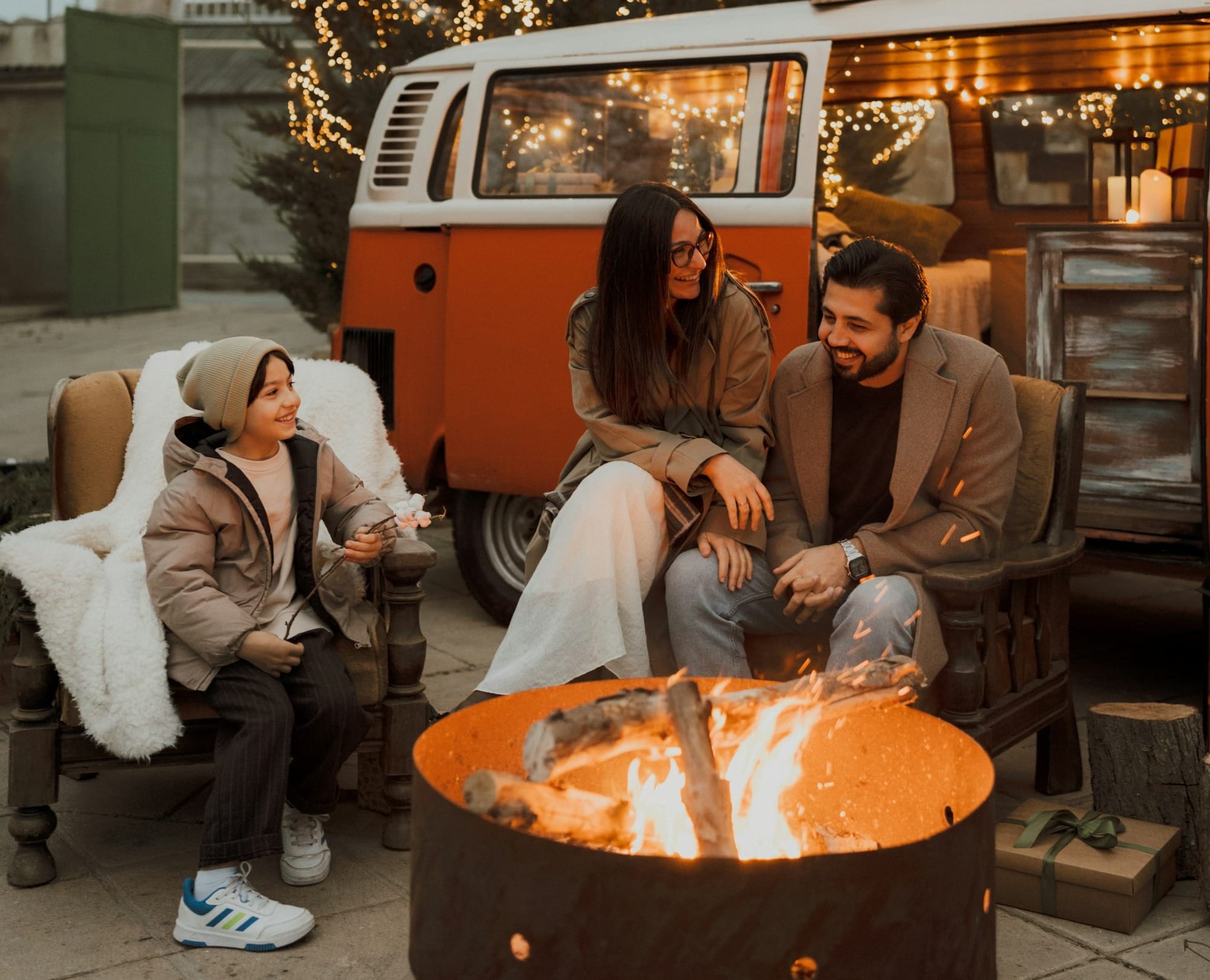 Family gathered around a campfire near a camper van